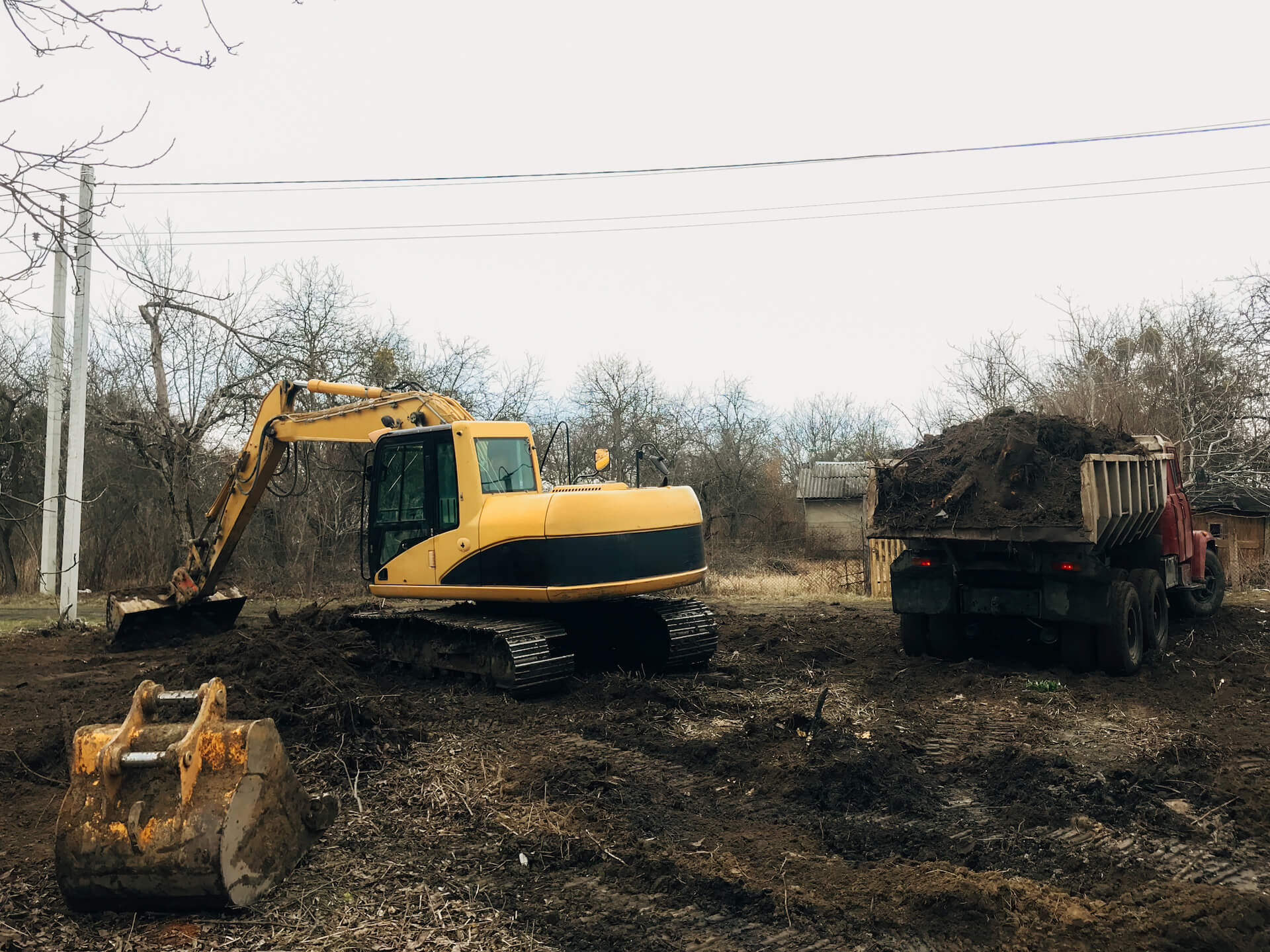 Bulldozer clearing a property and dumping earth into a truck | Featured image for the Warehouse Demolition Landing Page for Gumdale Demolition.