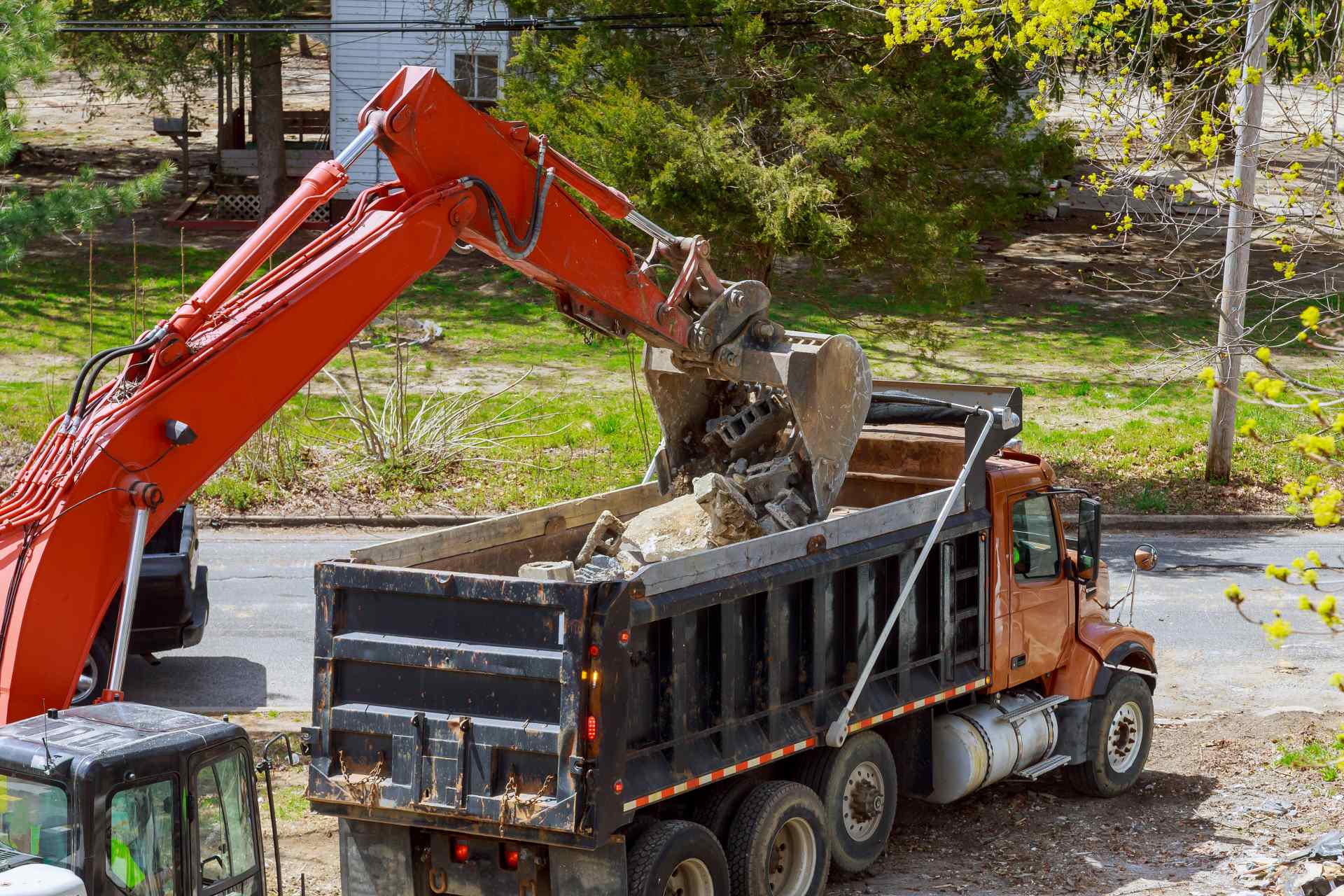 Excavator loading rubble into a truck | Featured image for The How Much Does It Cost to Demolish a House blog by Gumdale Demolition.