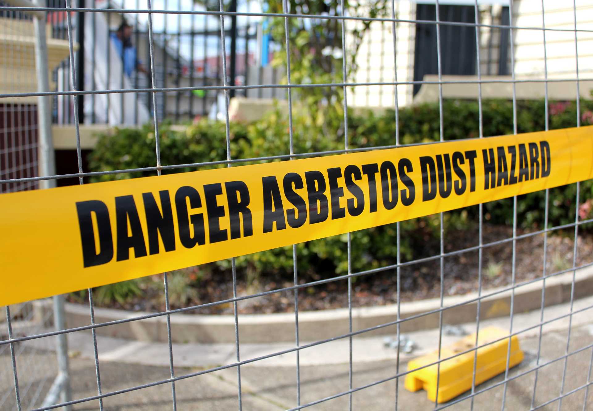 Asbestos removal warning tape across a fence | Featured Image for the Understanding the Asbestos Decontamination Process Blog by Gumdale Demolition.